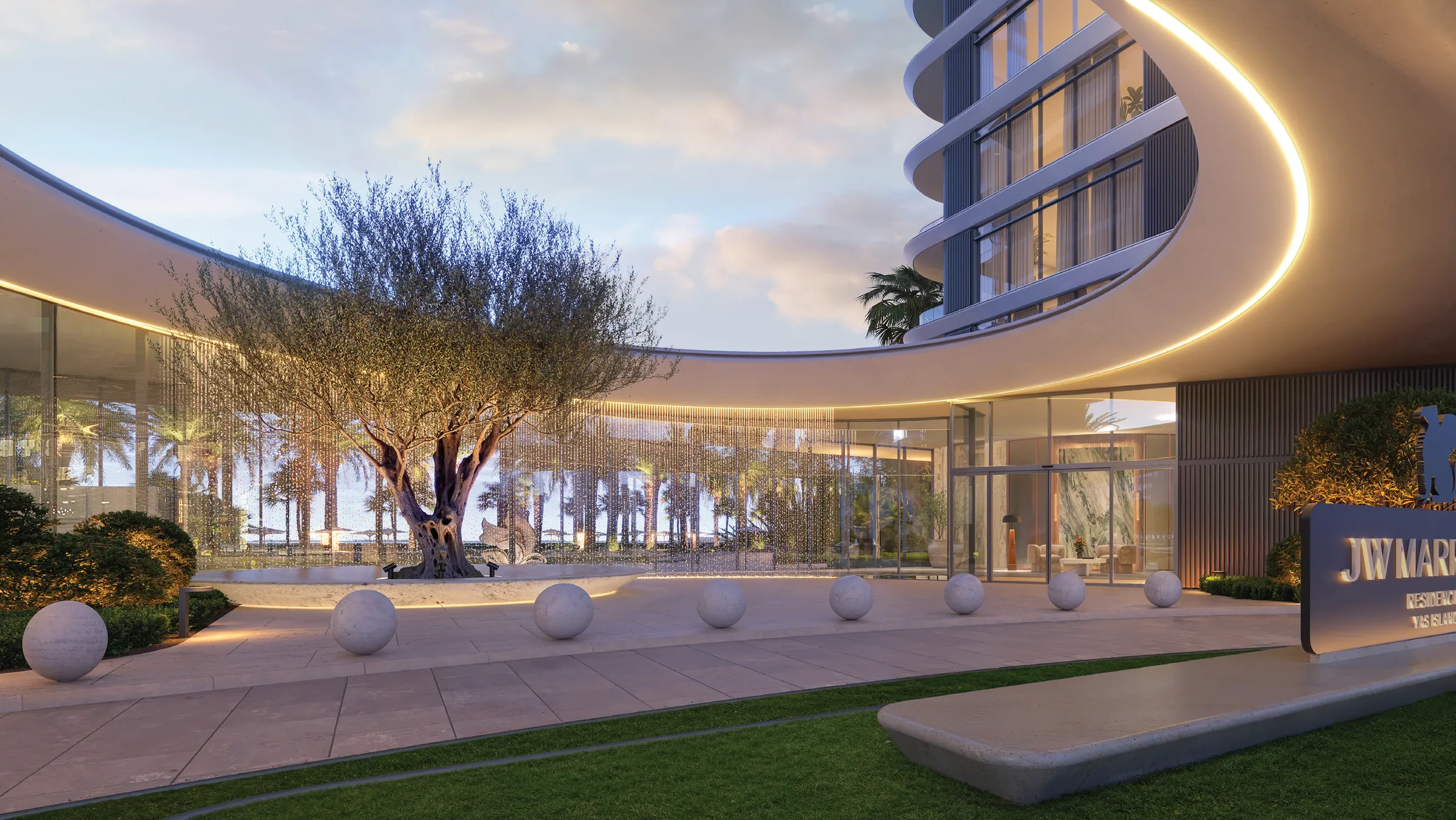 The arrival court: a curved canopy lit from beneath, an old olive tree and the residence entrance